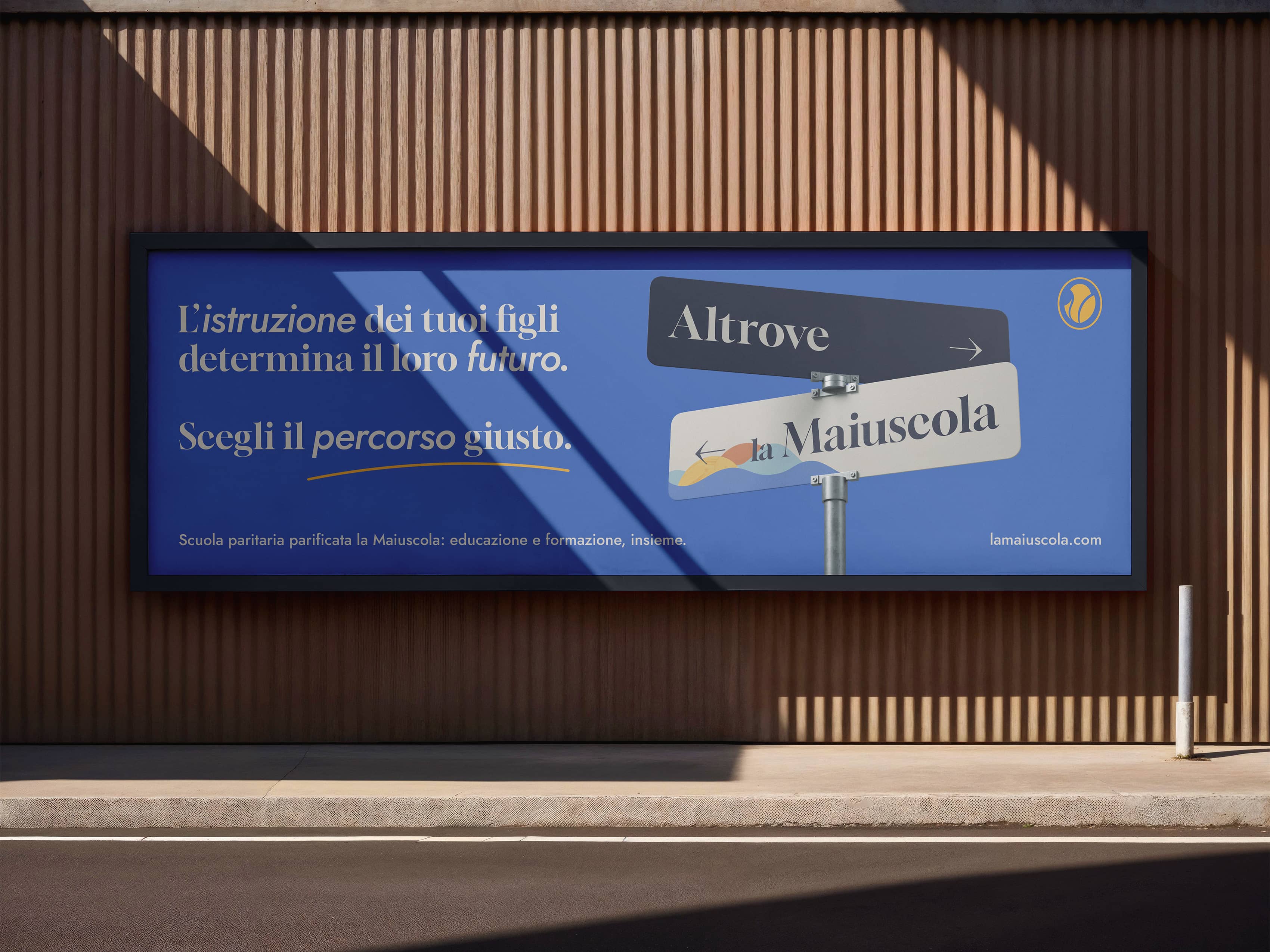 Outdoor billboard with Italian text promoting education featuring two directional street signs labeled 'Altrove' and 'la Maiuscola'.