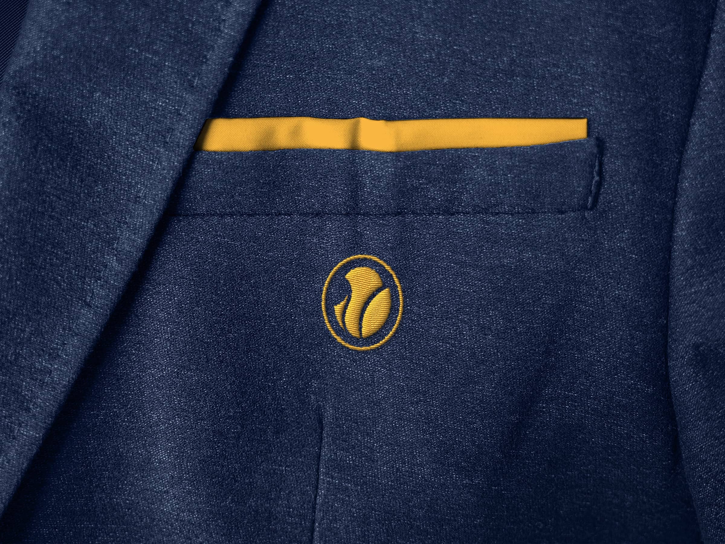 Close-up of a navy blue blazer pocket with a yellow pocket square and a yellow embroidered logo below the pocket.