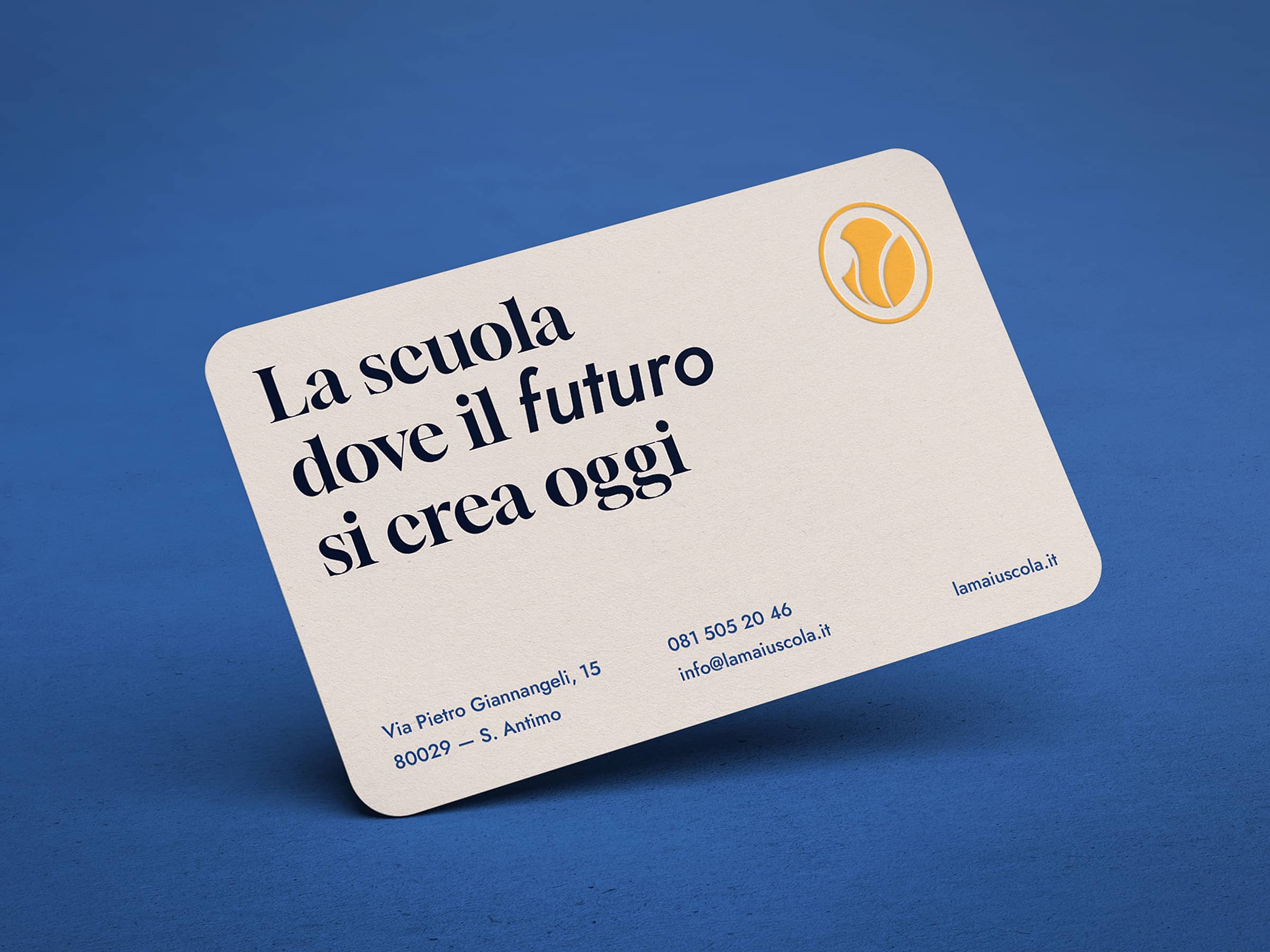 Business card with the text 'La scuola dove il futuro si crea oggi,' contact details, and a yellow circular logo on a blue background.